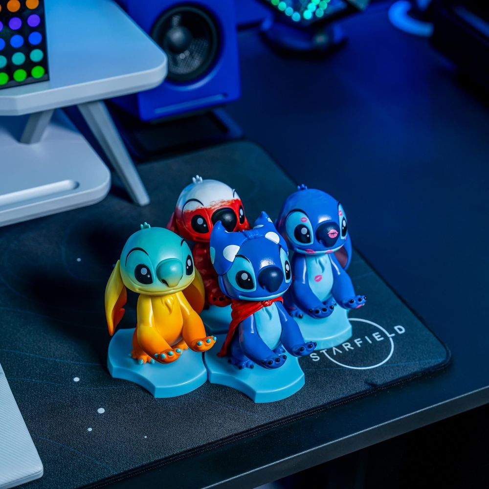 Quattro statuette di Stitch in diversi colori su un tappetino nero con accenti blu.