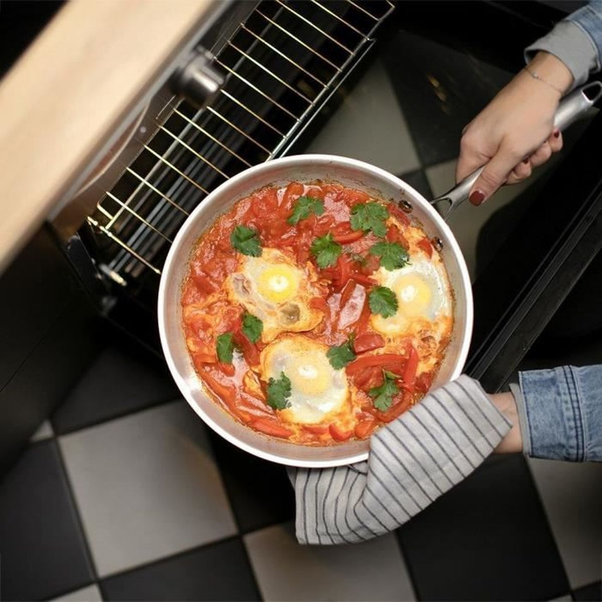 Pfanne mit Shakshuka, Eiern, Tomaten und Koriander in einem Ofen.