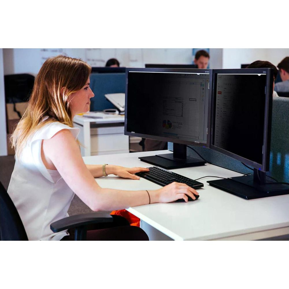 Una donna seduta a una scrivania usa due monitor del computer.
