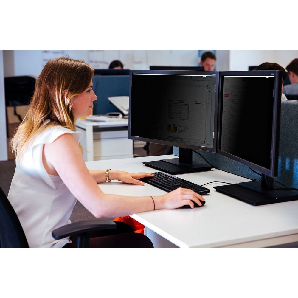 Frau in weißem Oberteil tippt auf Tastatur am Schreibtisch mit zwei Monitoren.