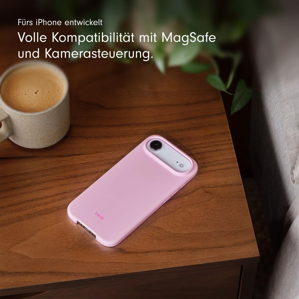 Różowe etui na iPhone leży na drewnianym stole obok filiżanki kawy.