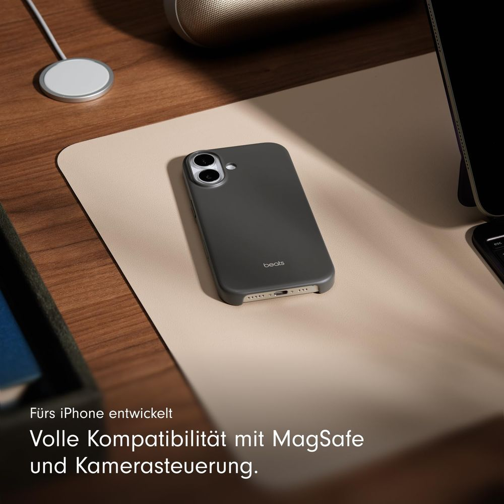 Graue iPhone-Hülle mit Beats-Logo auf hellem Untergrund, neben MagSafe-Ladegerät.