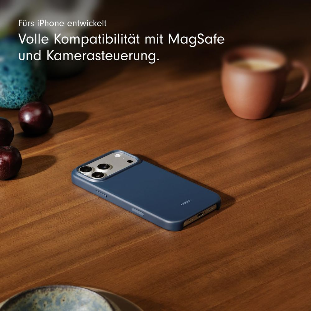 Niebieskie etui na iPhone na drewnianym stole obok owoców i kubka.