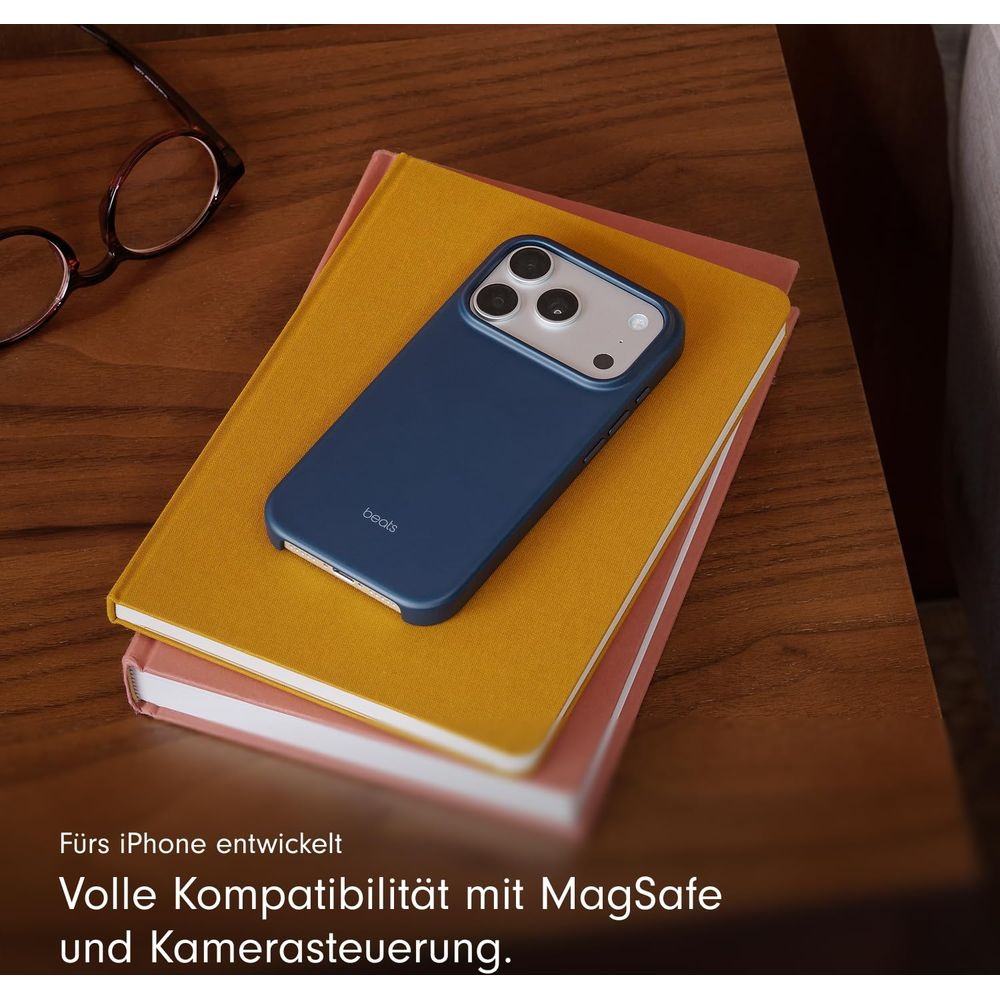 Niebieskie etui na iPhone leży na dwóch książkach, obok okulary.