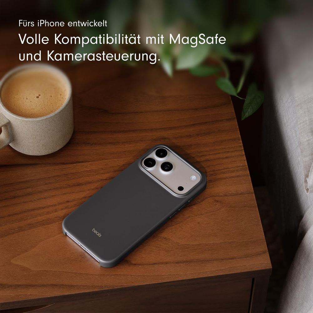 Una funda oscura para iPhone descansa sobre una mesa de madera junto a una taza de café.