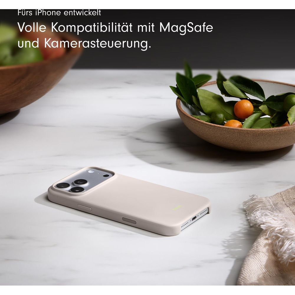Jasnobrążowe etui na iPhone leży na marmurze obok miski z pomarańczami i liśćmi.