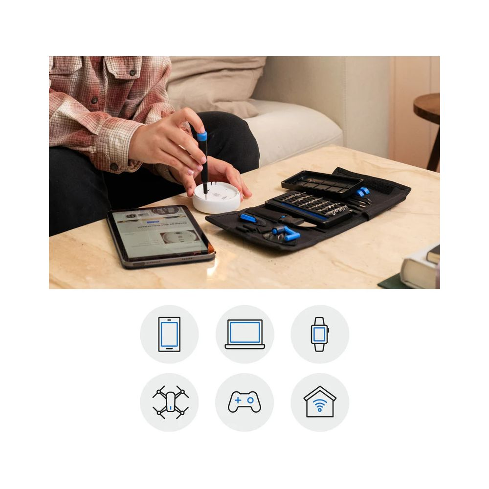 Person benutzt Schraubendreher an weißem Gerät neben Werkzeugkasten und Tablet.