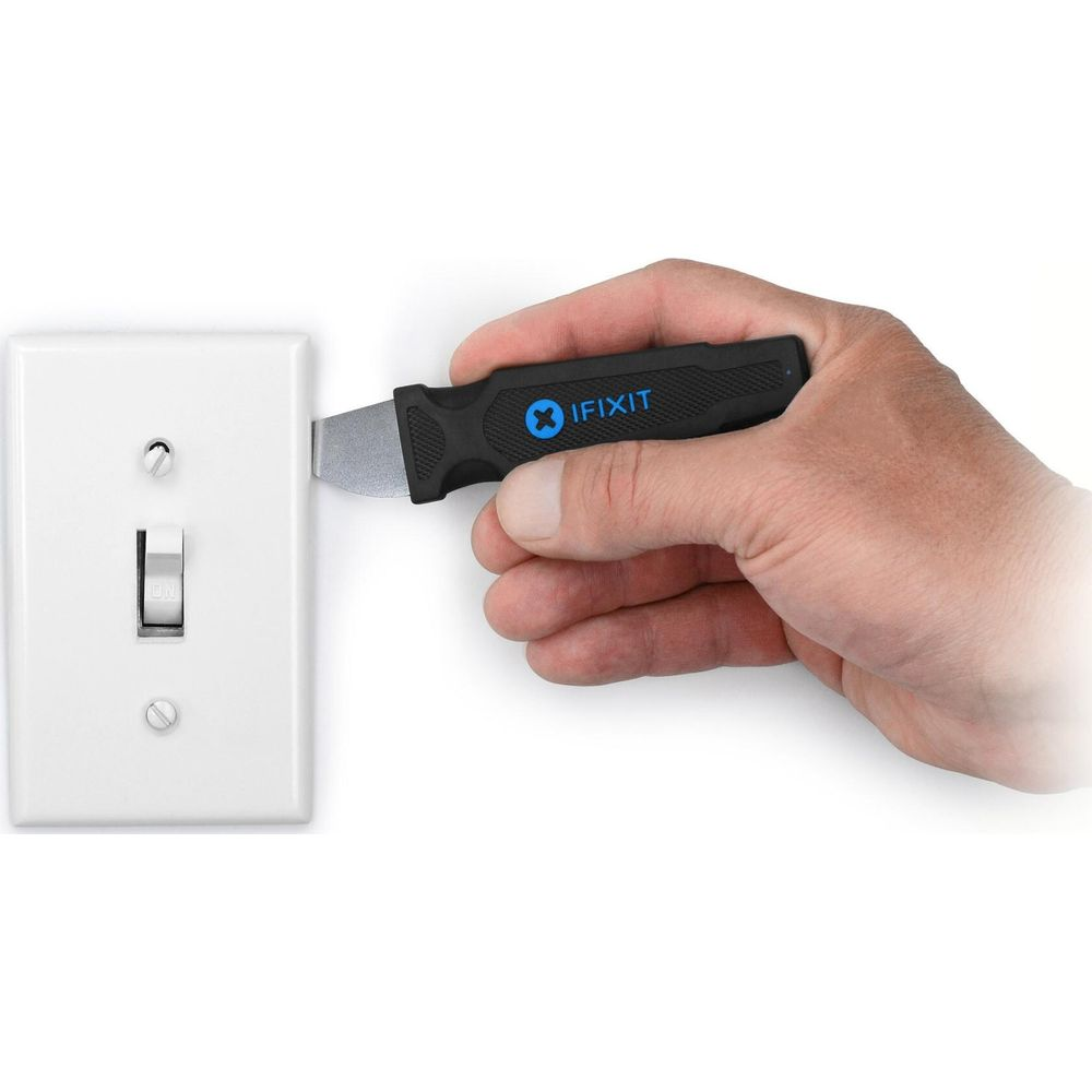 Hand hält iFixit-Werkzeug neben Lichtschalter.