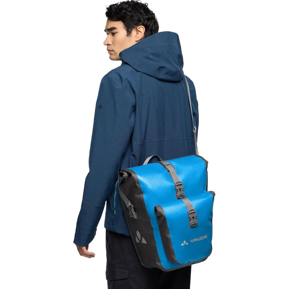 Mężczyzna noszący niebieski zestaw sakw rowerowych na ramieniu.