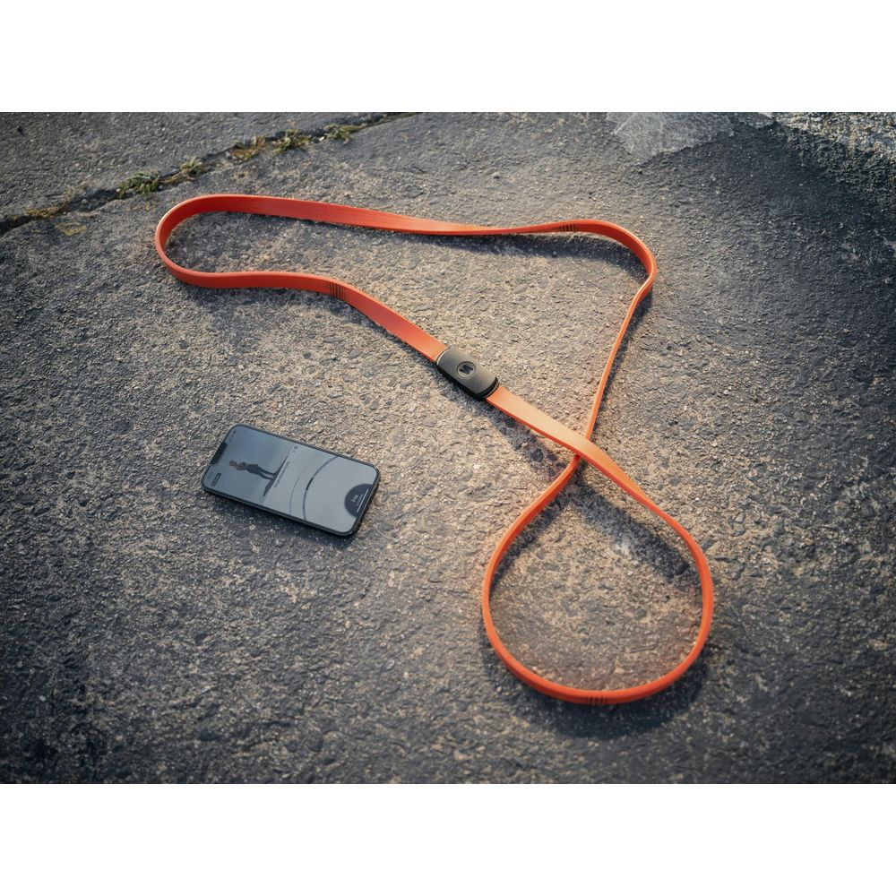 Un cordon orange et un smartphone sont posés sur un sol asphalté.