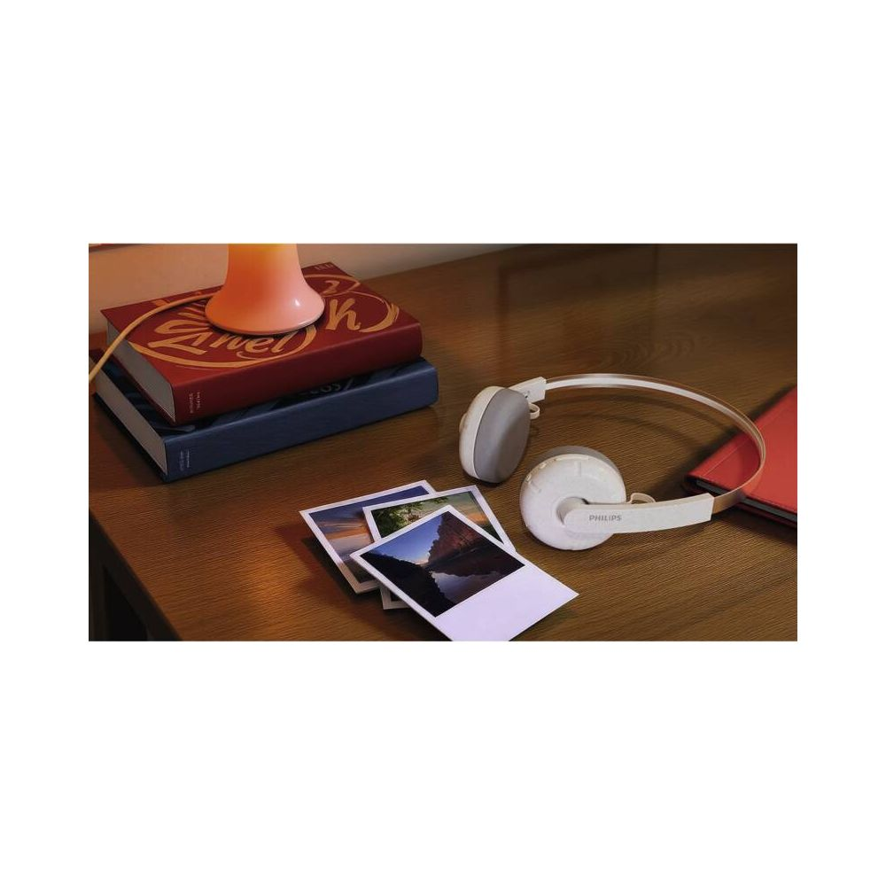 Casque blanc posé près de livres et de photos sur une table en bois.