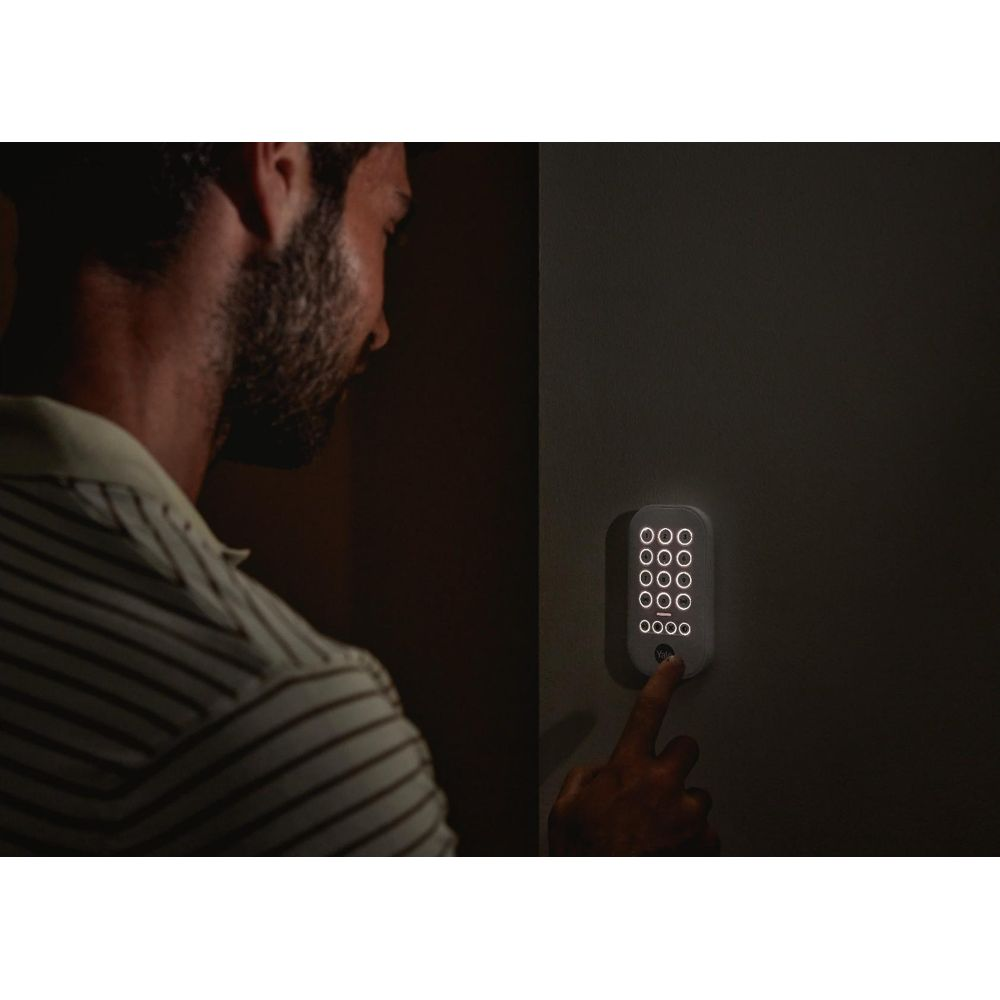 Uomo preme un tastierino illuminato su un muro scuro.