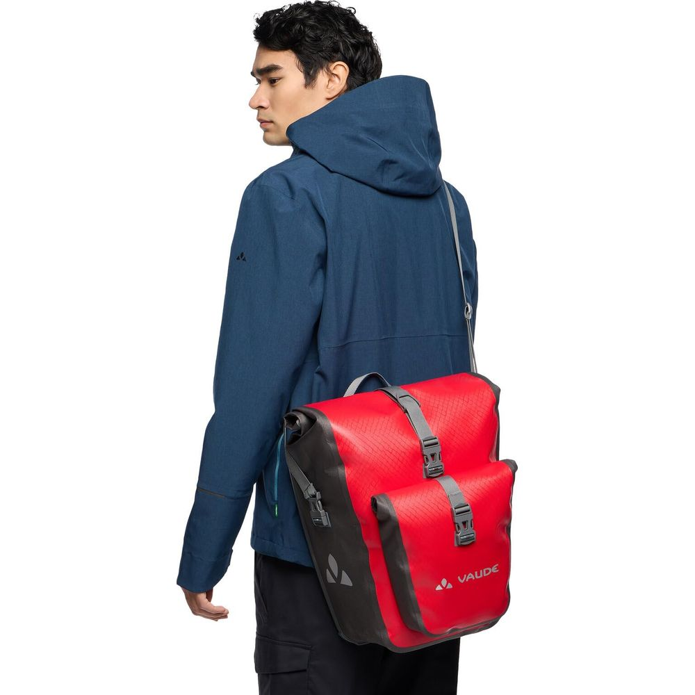 Mann mit blauem Anzug und roter Fahrradtasche auf der Schulter.