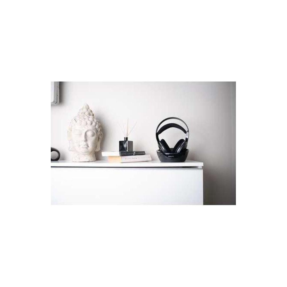 Una estatua de Buda blanca y auriculares en un estante blanco.