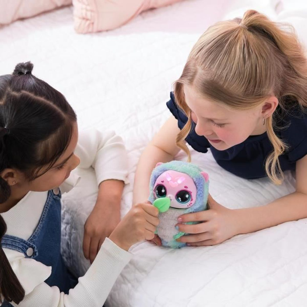 Dos niñas juegan con un juguete esponjoso en una cama.