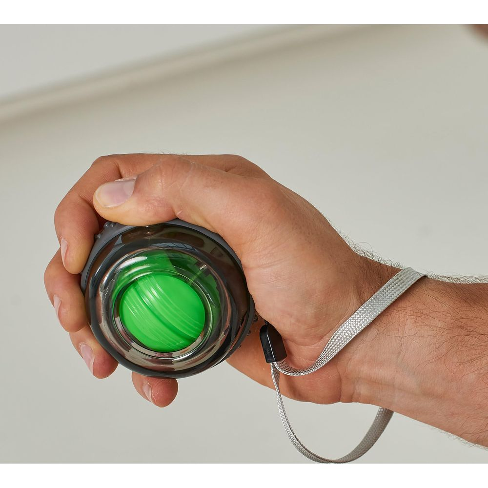 Une main tient un exercice de poignet gyroscopique vert avec dragonne.