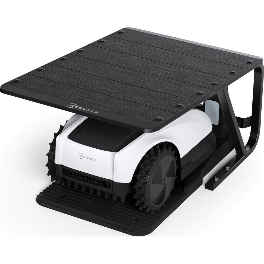 Un robot tosaerba bianco e nero con ruote robuste sotto una struttura in legno scuro.