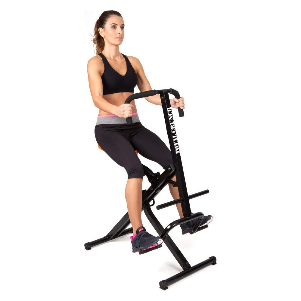 Donna si allena su una macchina Total Crunch, indossa top nero e leggings.