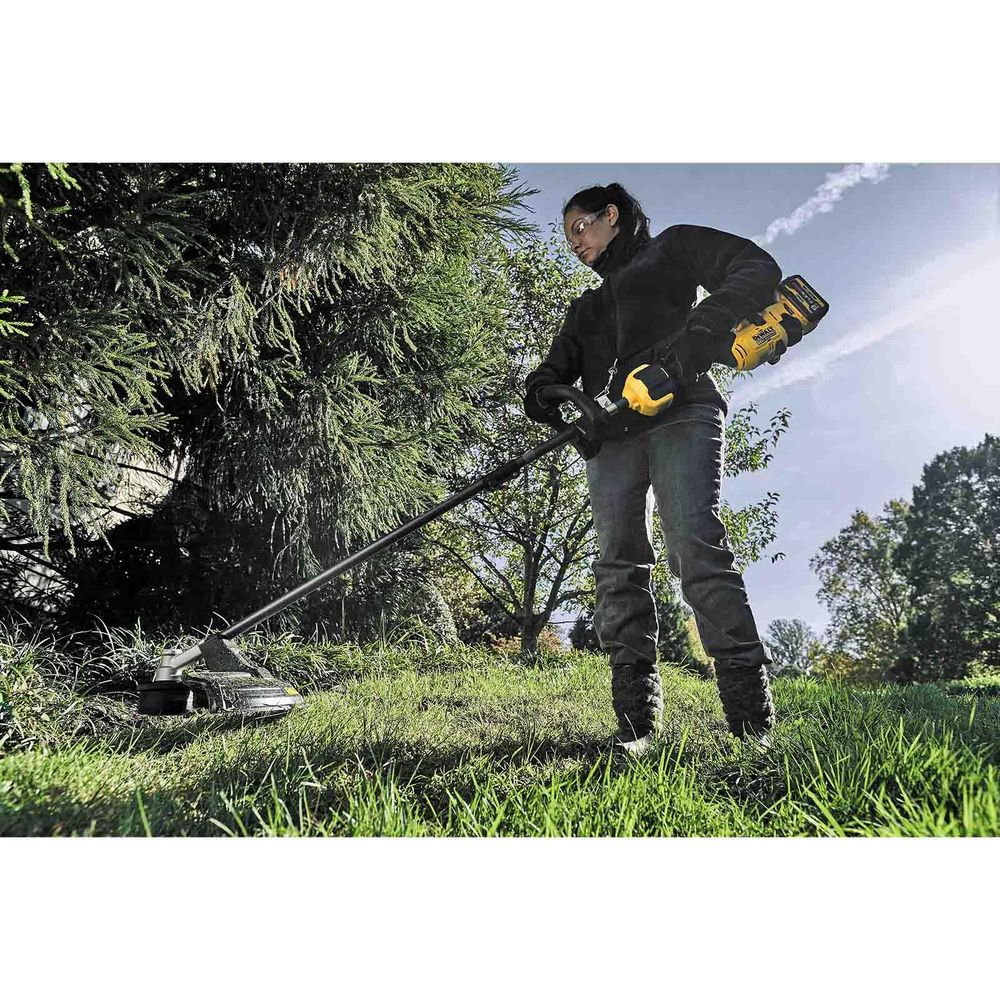 Kobieta na zewnątrz używa podkaszarki do cięcia trawy.