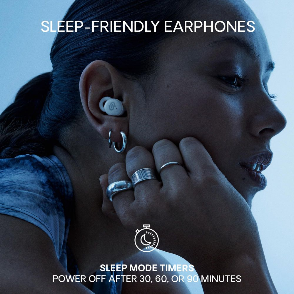 Kobieta z białymi słuchawkami w uchu, trzymająca się za podbródek.