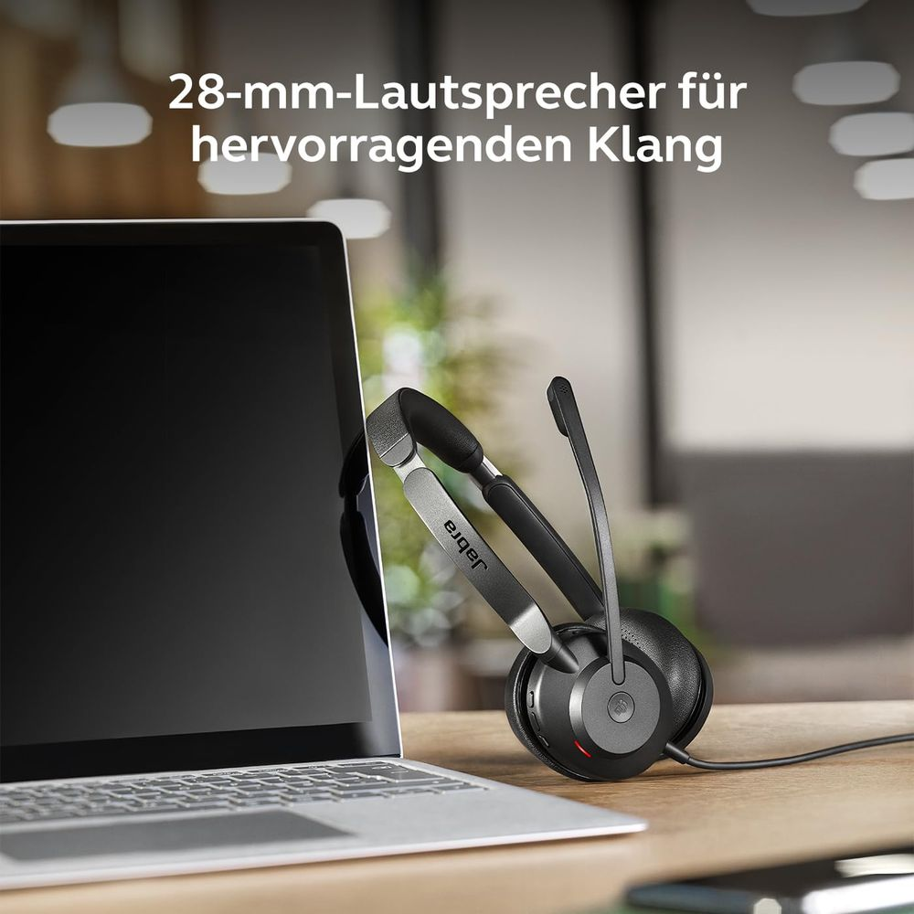 Zestaw słuchawkowy Jabra z mikrofonem obok laptopa na drewnianym biurku.