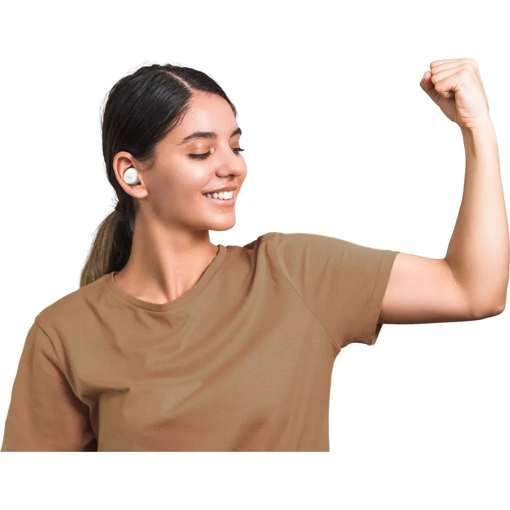 Kobieta ze słuchawkami w brązowej koszulce napinająca biceps.