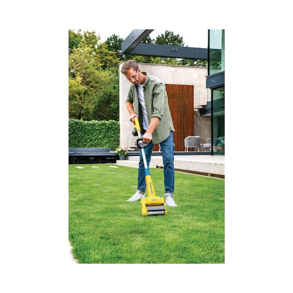 Mężczyzna przycina trawnik żółtą podkaszarką w ogrodzie.