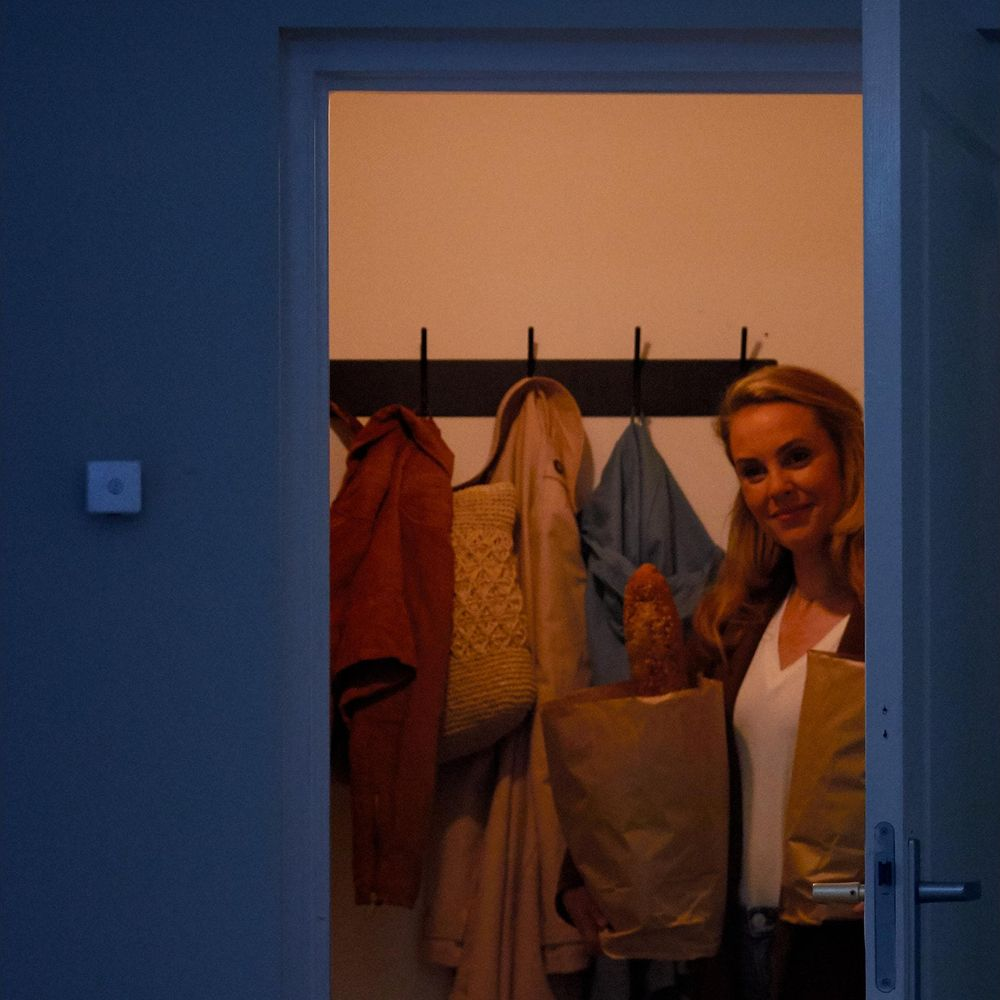 Kobieta trzyma torby z zakupami przed płaszczami na wieszaku.