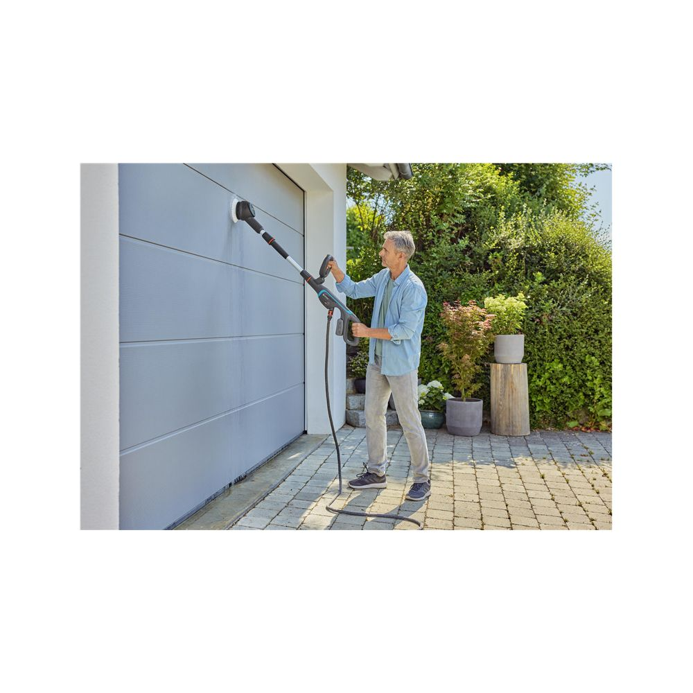 Un uomo pulisce una porta del garage con un'idropulitrice.