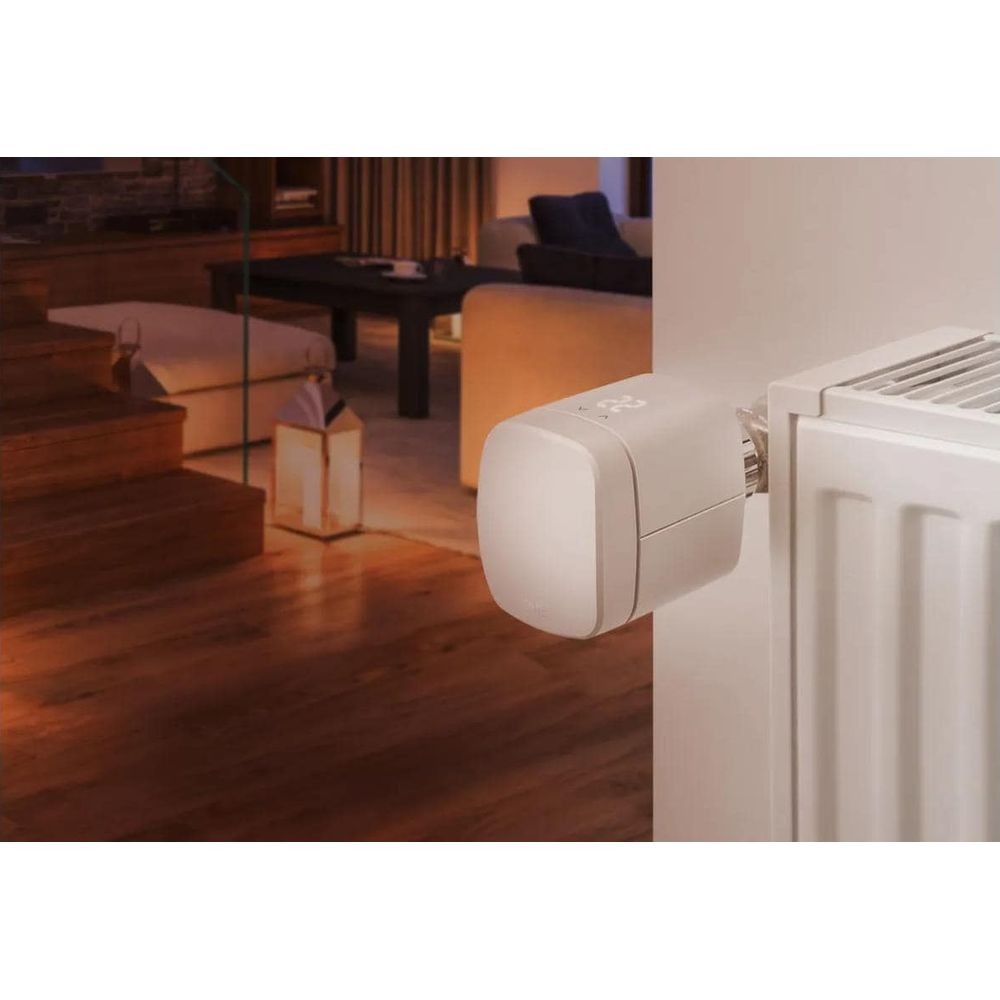 Ein weißer Heizkörperthermostat mit digitaler Anzeige ist an einem Heizkörper montiert.