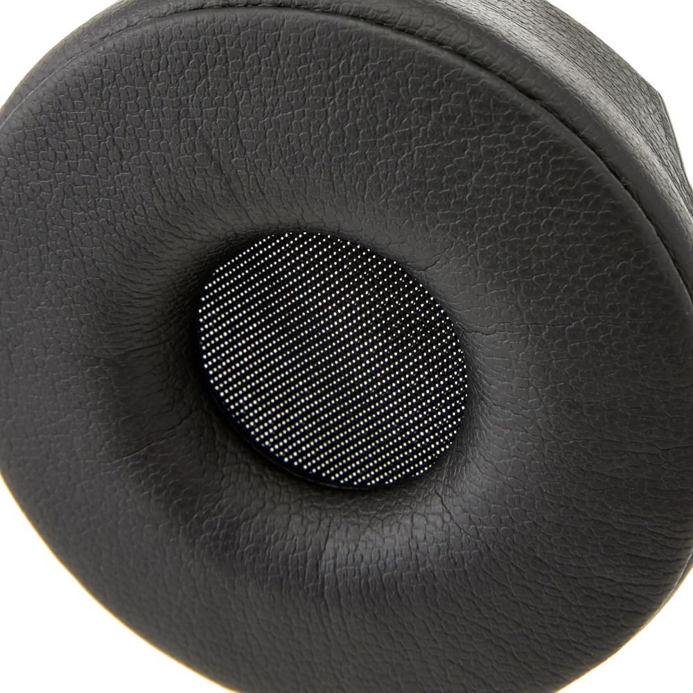 Primo piano di un cuscinetto per cuffie nero con griglia dell'altoparlante perforata.