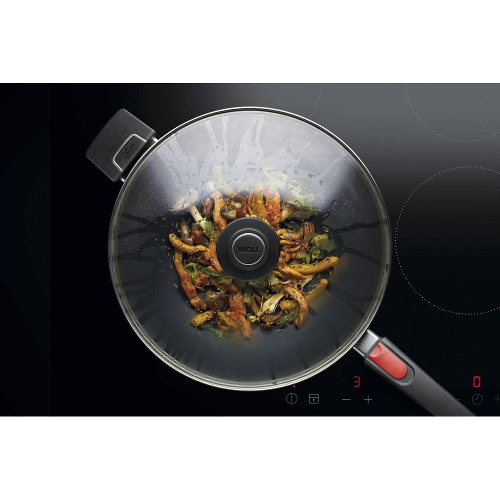 Ein Wok mit Essen und Deckel auf einem Induktionskochfeld.