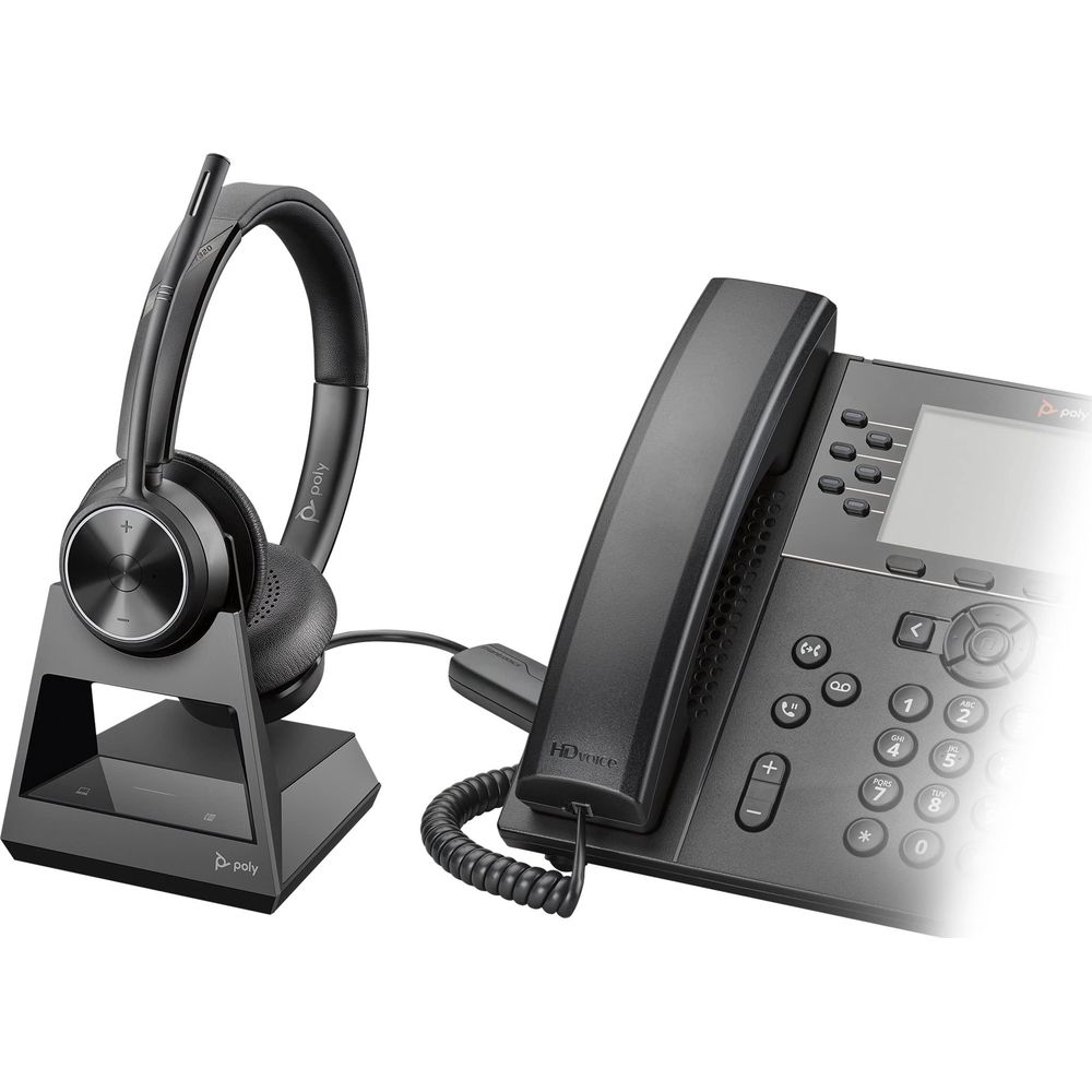 Un auricolare wireless nero su una base di ricarica accanto a un telefono da scrivania nero.