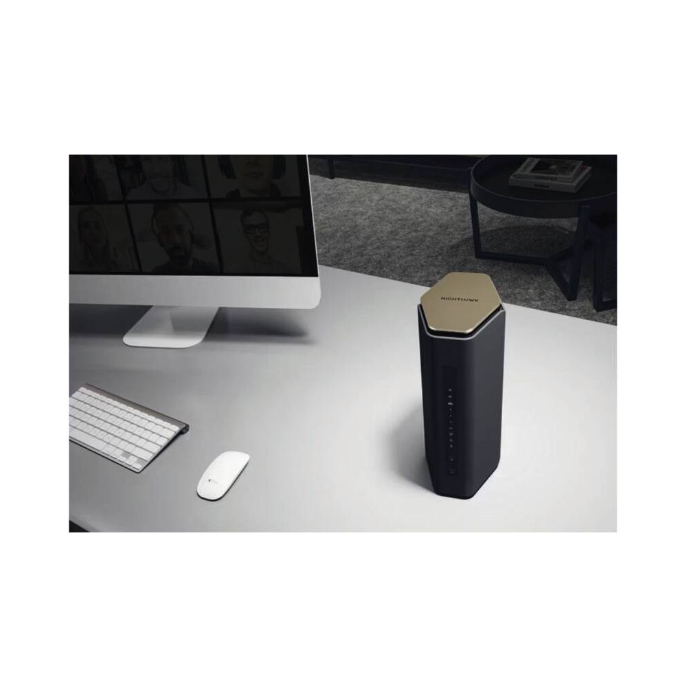 Ein schwarzer Nighthawk-Router mit goldener Oberseite steht auf einem Schreibtisch neben einem Computer.