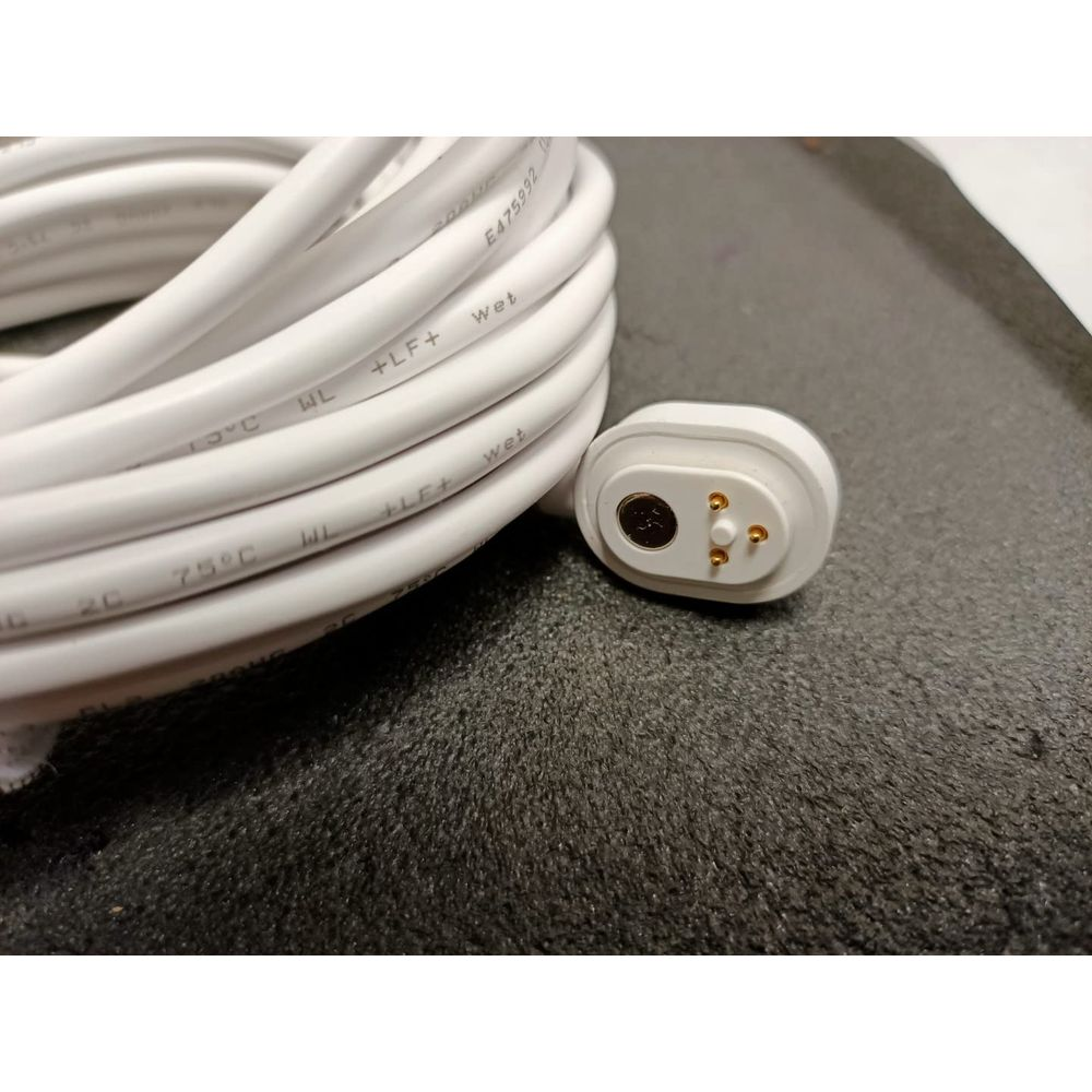 Weißes Kabel mit Magnetstecker und drei Pins auf dunklem Hintergrund.