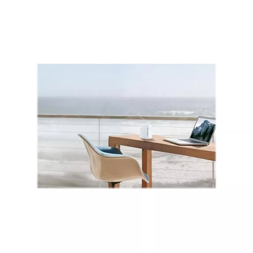 Laptop i biały pojemnik na drewnianym stole nad morzem.