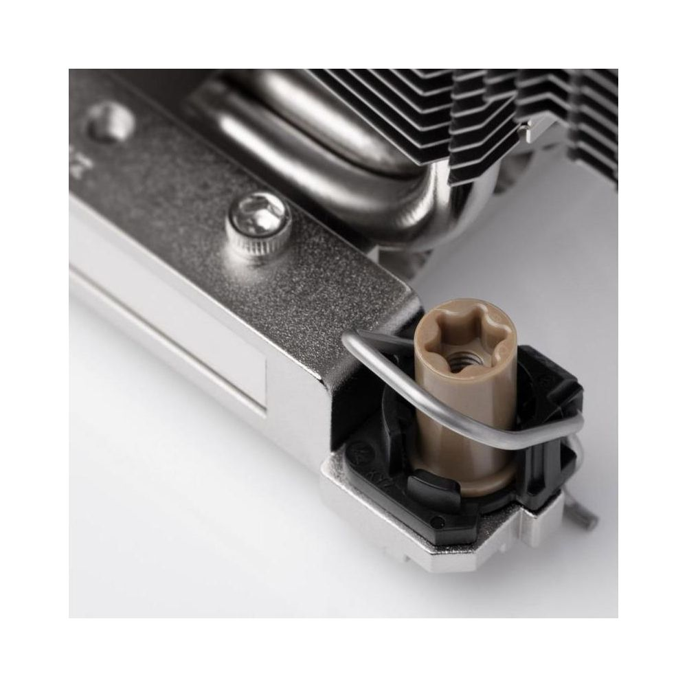 Gros plan d'un refroidisseur de CPU avec des ailettes argentées et une goupille de montage beige.