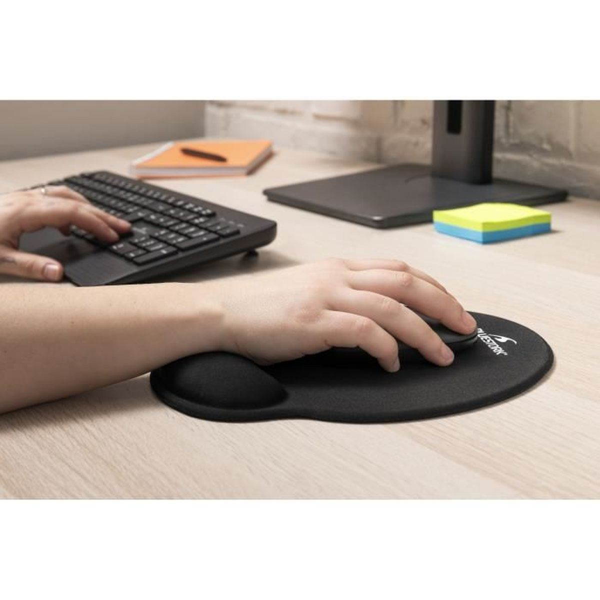 Person benutzt eine Maus und Tastatur auf einem Schreibtisch mit Mauspad.