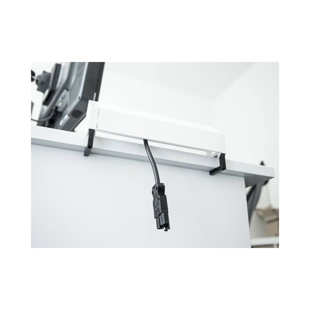 Ein schwarzes Kabel mit Stecker hängt von einem weißen Kasten, der an einem Schreibtisch befestigt ist.