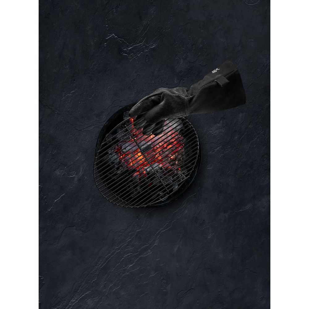 Gegrillte Kohlen mit einer schwarzen Handschuh auf dunklem Hintergrund.