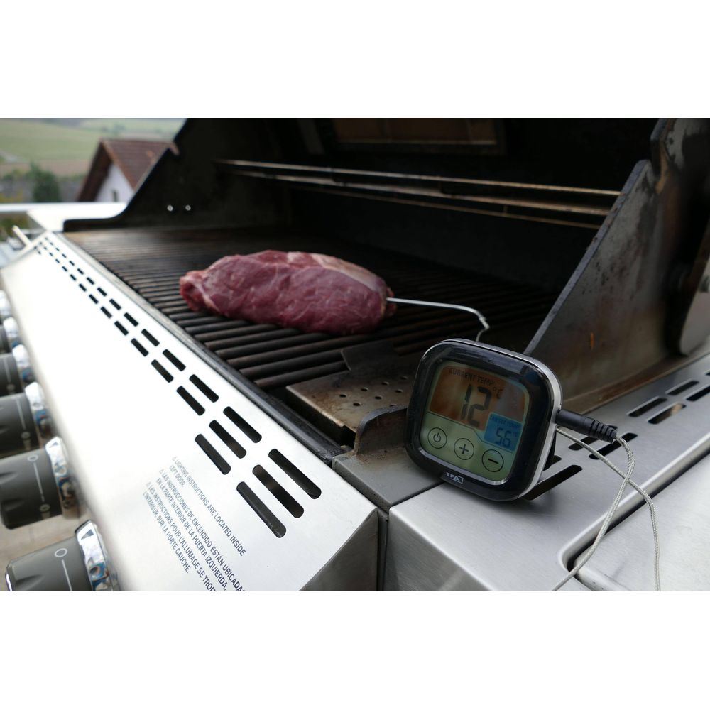 Ein roher Rinderbraten liegt auf einem Grill mit einem digitalen Thermometer daneben.