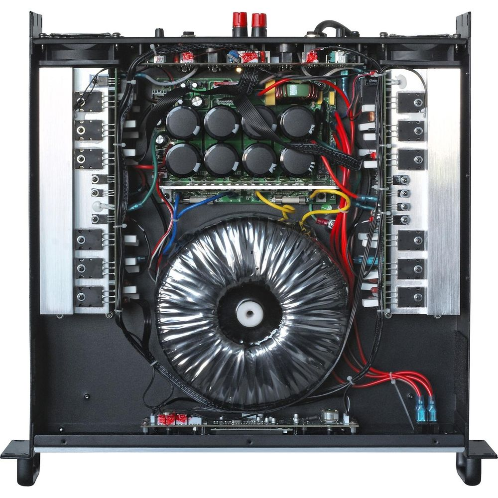 Vista interior de un amplificador con transformador grande, condensadores y cables.