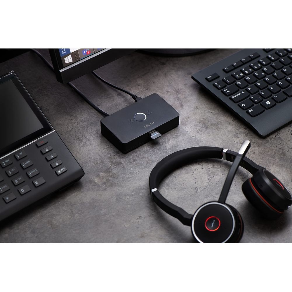 Un Jabra headset, teclado, teléfono y adaptador Jabra sobre una mesa.