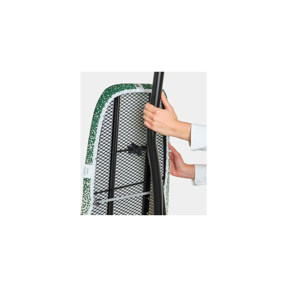 Mains installant une planche à repasser à motif vert.