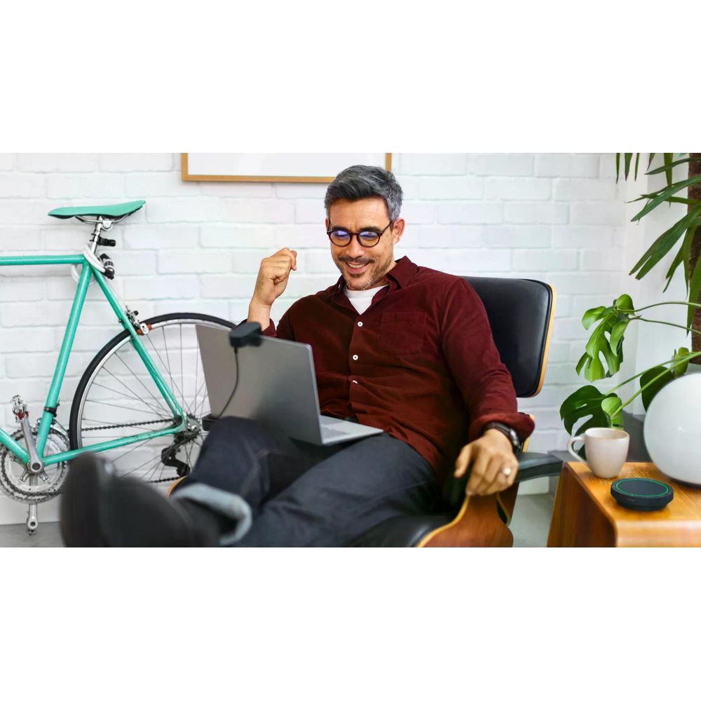 Mężczyzna siedzi w fotelu, pracuje na laptopie. Obok stoi rower.