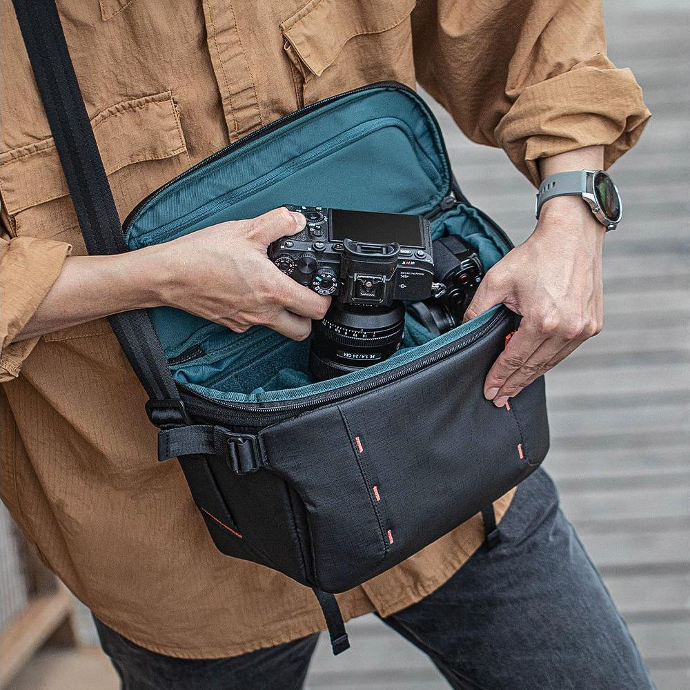 Una persona mette una fotocamera in una borsa nera con fodera interna turchese.