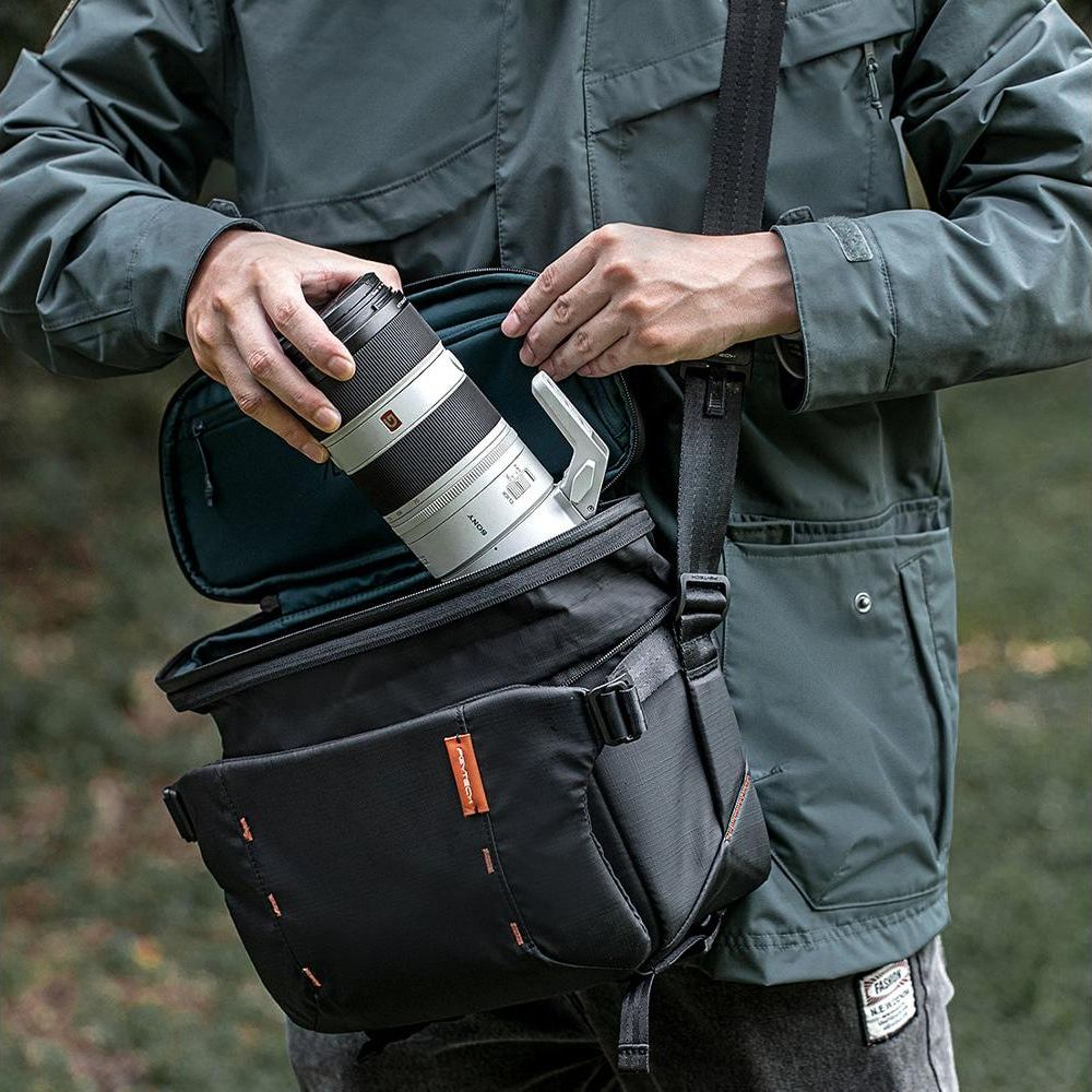 Una persona mette un obiettivo bianco in una borsa fotografica nera.