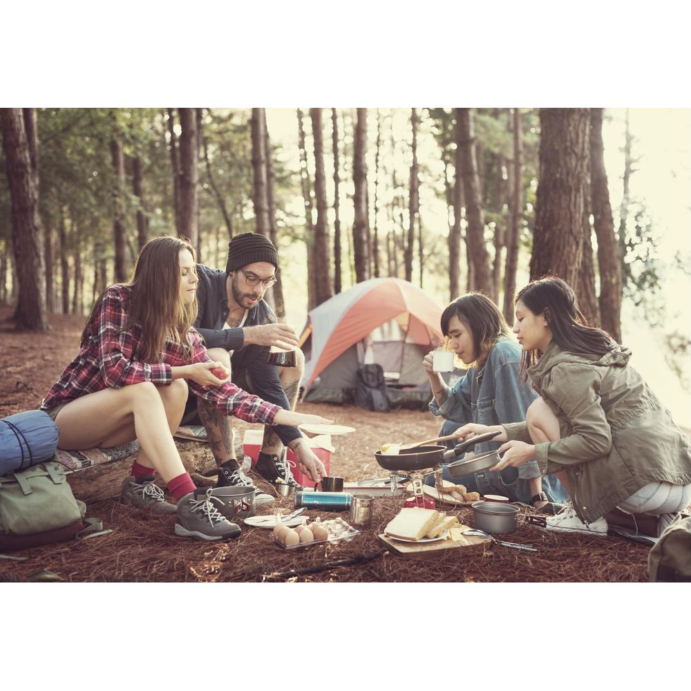 Cuatro amigos acampando y cocinando en un bosque. Una tienda de campaña al fondo.