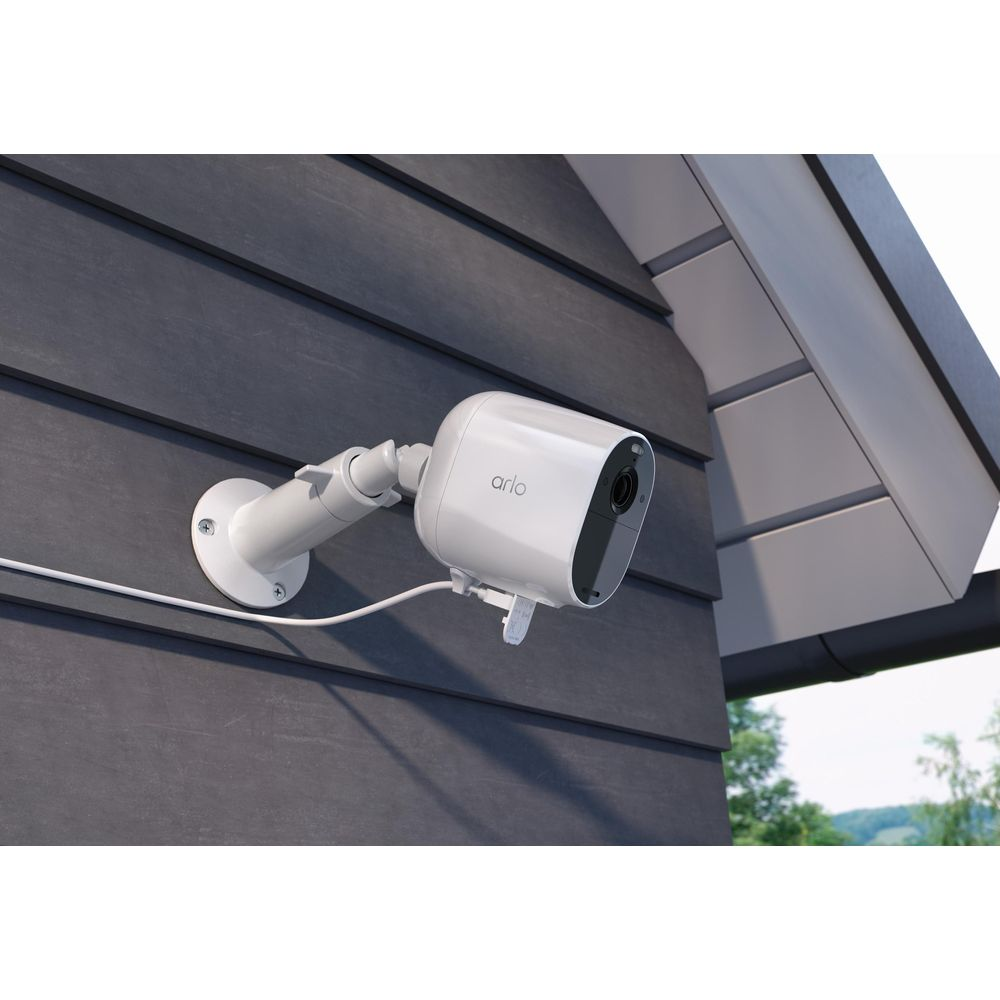 Eine weiße Arlo-Kamera ist an einer dunklen Hauswand montiert.