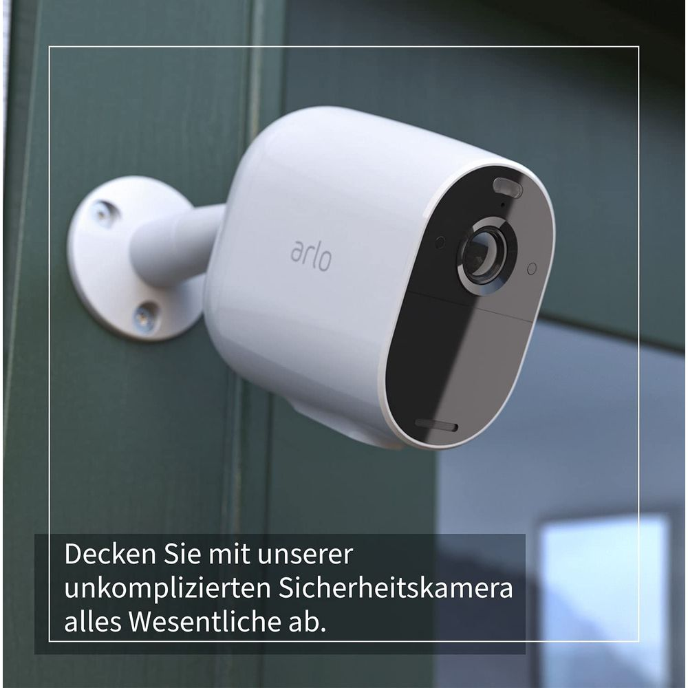 Eine weiße Arlo-Überwachungskamera ist an einer dunkelgrünen Wand montiert.